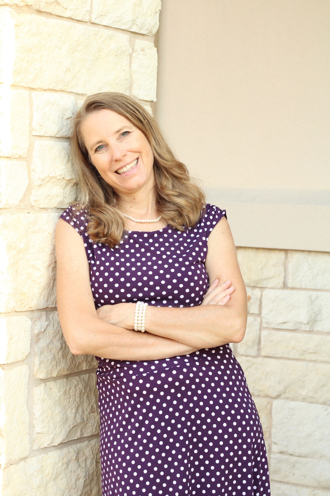 Dr. Sears smiling by a stone wall
